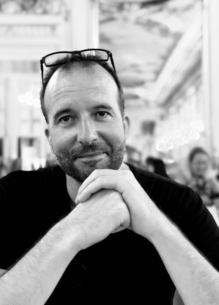 Valentin Schmalzried mit einem leichten Lächeln, die Hände vor sich gefaltet – Schwarzweißporträt